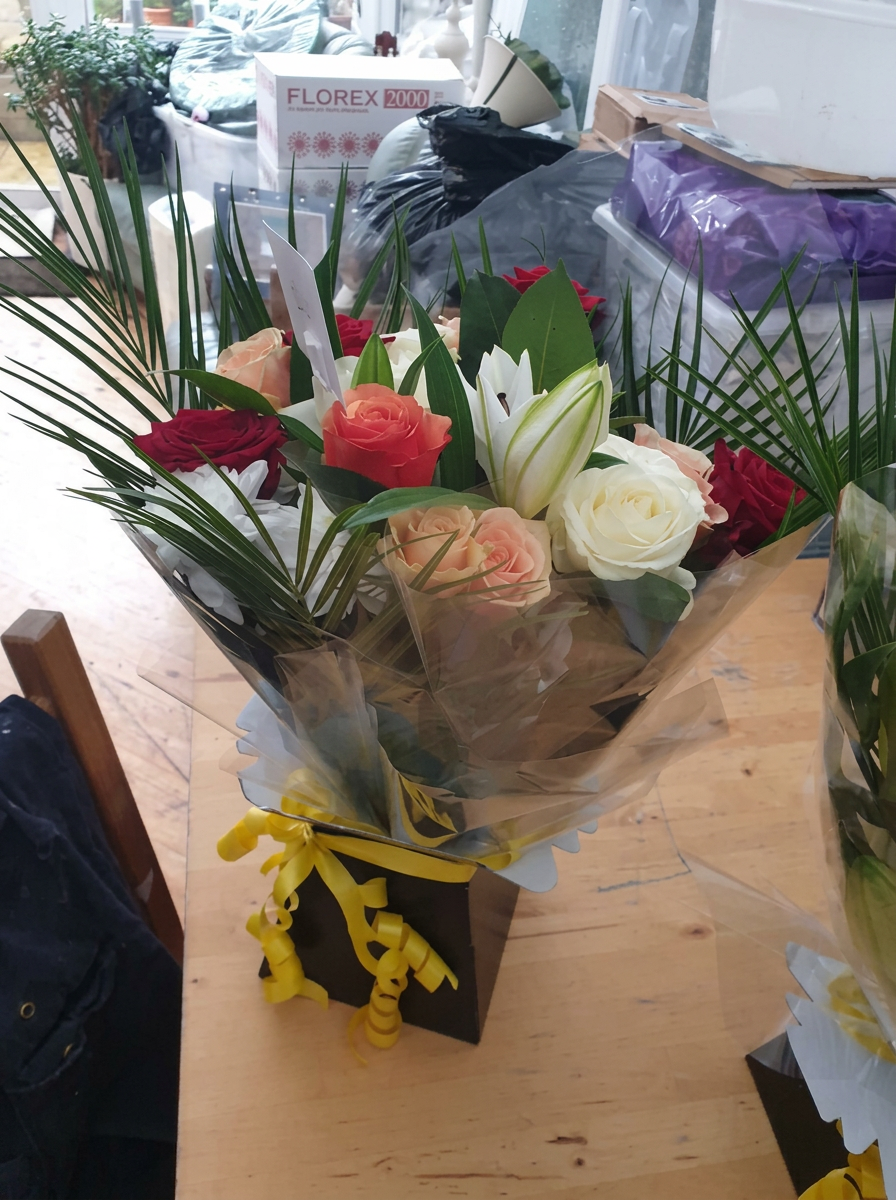 Mixed seasonal bouquet with a yellow ribbon by Anne's Florist.