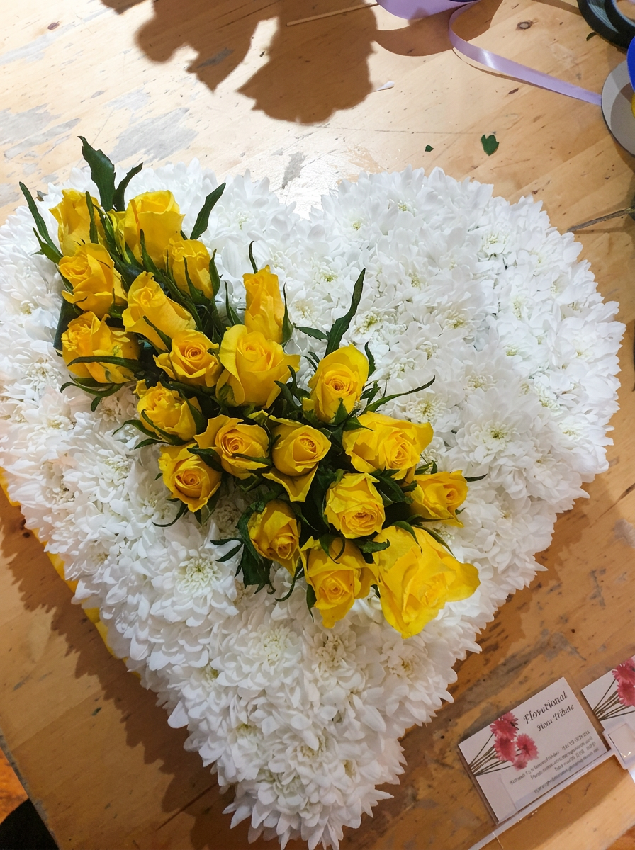 Yellow heart-shaped floral tribute by Anne's Florist.